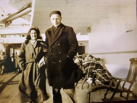 A sepia-toned photo of a white Dutch man and woman in nice jackets on a ship deck.