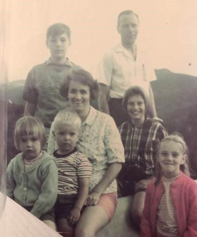 An old photo of a white family posing outdoors, including a man, woman, and five children of various ages.