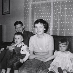 Young man and woman sitting on a couch with a little boy and a girl. 