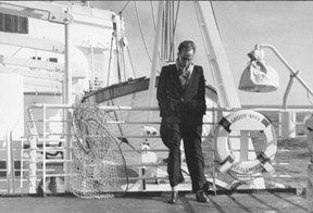 Man leaning against railing of ship.