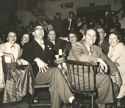 Large group of people sitting and smiling and laughing in front of the camera.
