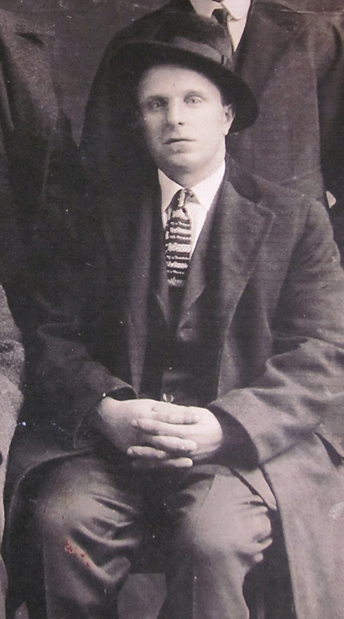 Young man wearing hat and black coat stiing with cross hands.