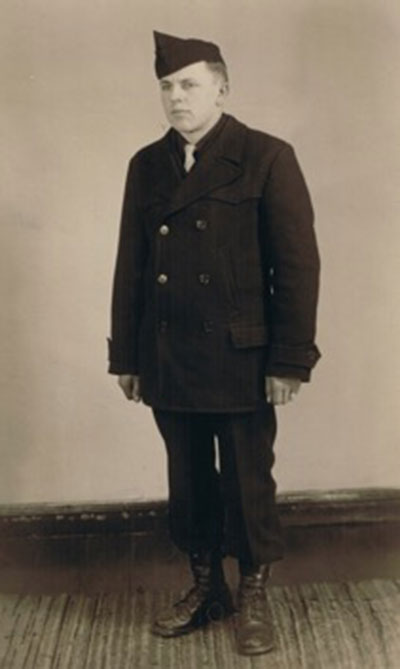 A young man is wearing a uniform and standing in front of a wall.