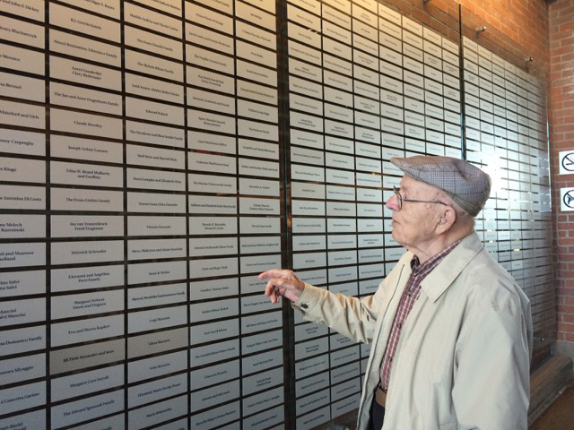 A man stands in front of the Sobey's Wall of Honour in the Canadian Museum of Immigration at Pier 21.