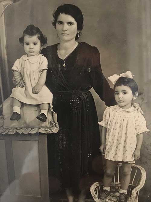 Black and white portrait of woman standing with two children seated next to her
