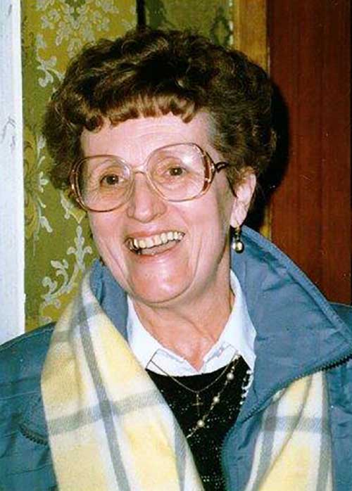 A laughing woman in big glasses looks off to the side.