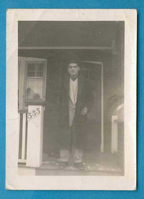 Young man standing in a porch withd house number 555 on his right side.