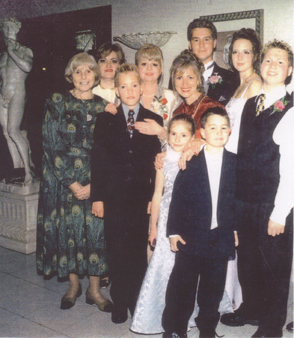 Several woman and children surrounding bride and groom on wedding day.