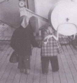 Two kids on the boat, turning their backs to the camera. 