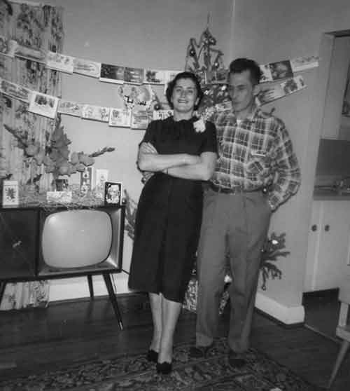 Couple is standing next to each other with greeting cards on the back wall and on top of television.