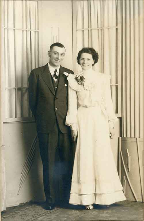 A couple on their wedding day, smiling happily at the camera.