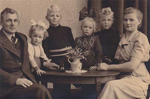 Man and woman with four kids sitting around the table.