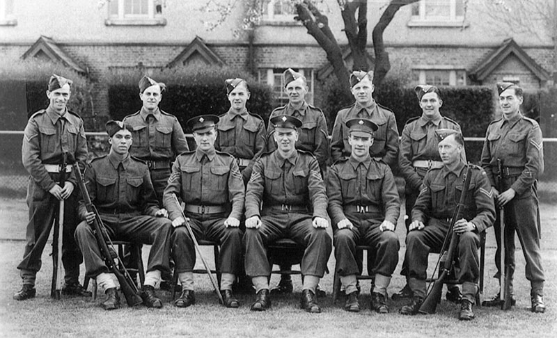 A large group of men in uniform pose for the camera, some seated and the others stand behind them.