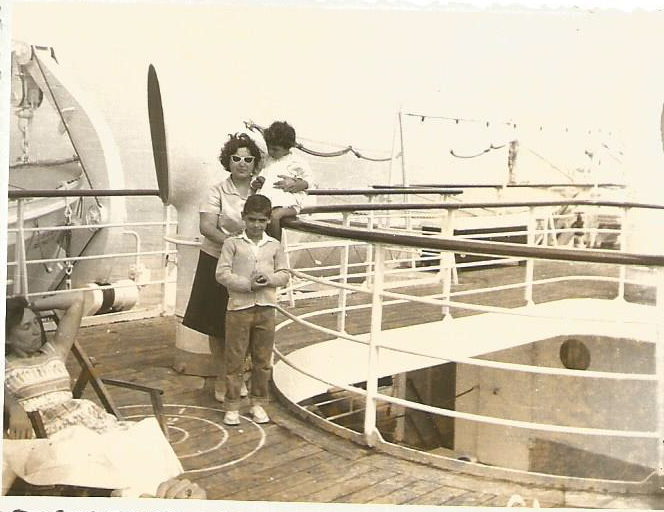 A woman and two children stand by the ship's railings.