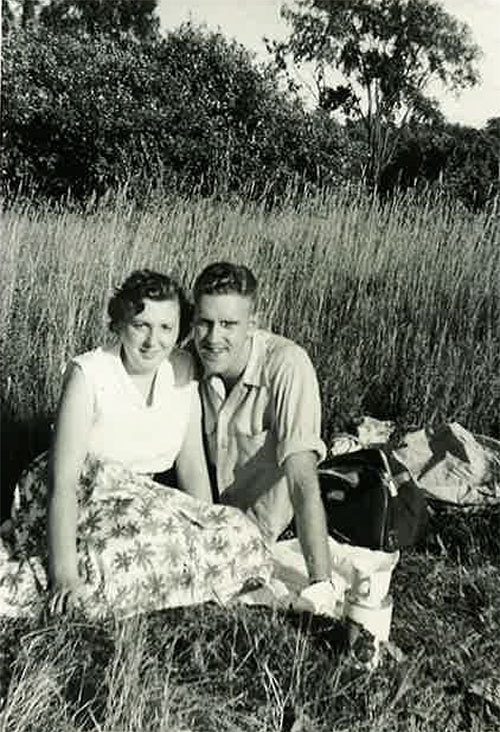 A young man and woman are having a picnic in the tall grass.