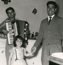Man holding hand of small girl with accordion player behind them.