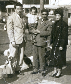 Outdoor photo of two men, one woman in black coat and small child in man's arms.