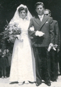 Full-length photo of bride and groom standing at church entrance.