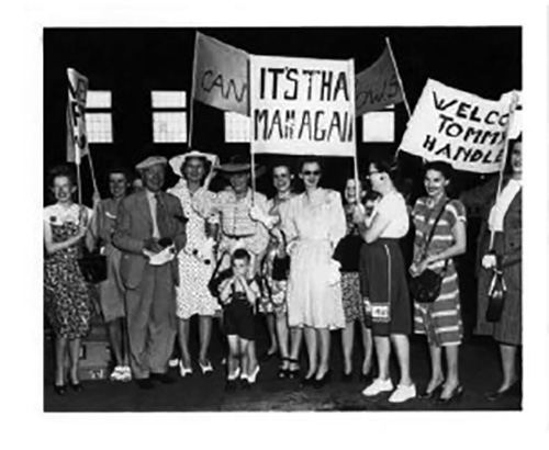Archival image showing several people holding up welcome signs.