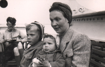 Mother with two children in lap, sitting on deck of ship.