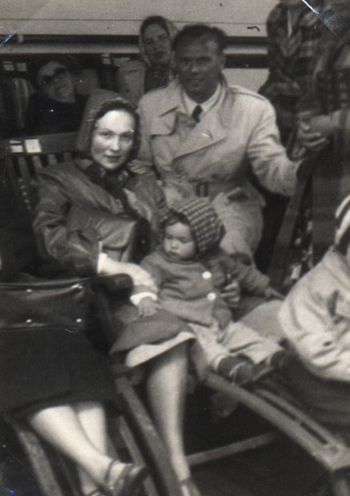 Mother and baby sitting in a deck chair, surrounded by other passengers.