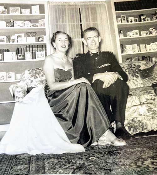 A young man and woman sit on a couch to have their photo taken.