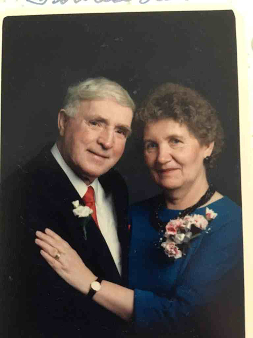 A middle-aged couple wearing corsages pose for the camera.