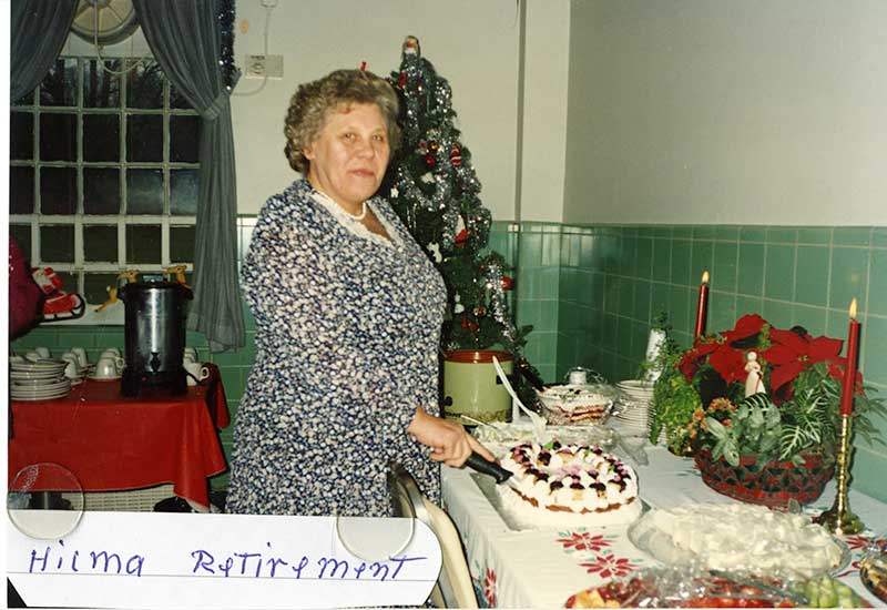 Woman standing in front of a table laden with Christmas decoration and food.