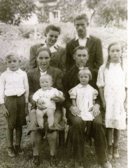 An archived family photo with four adults and four children.