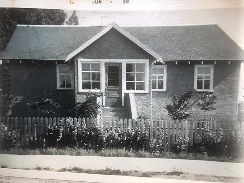 Archival image of a house with a picket fence around it.