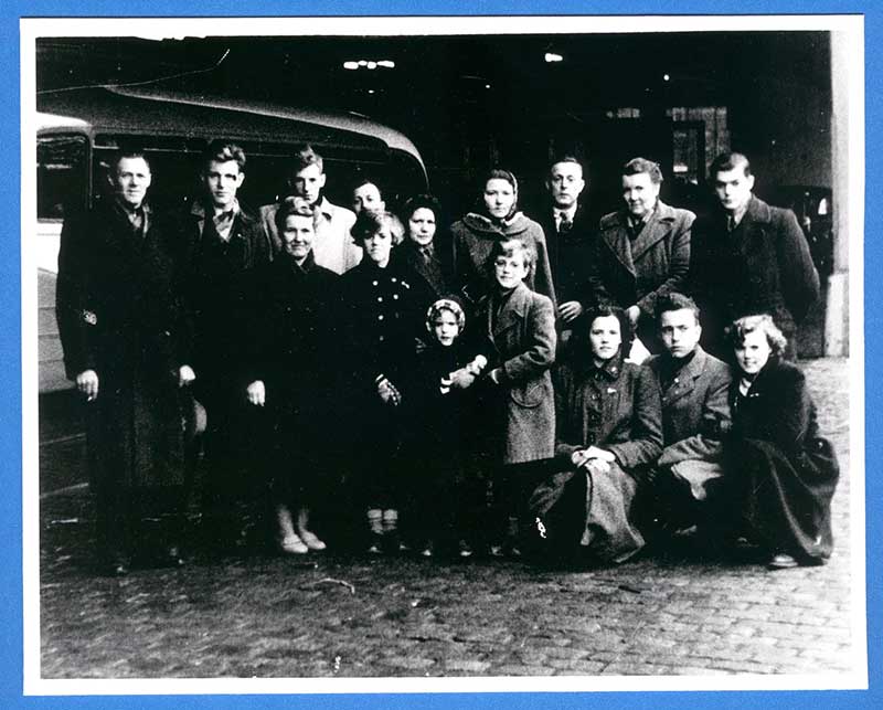 Black and white image of several men, women and children posing for the camera.