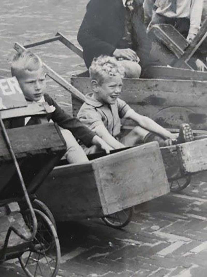 Two young boys sit in handmade carts.