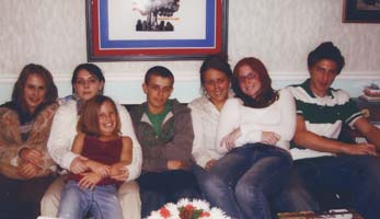 Young children and teenagers seated on couch.