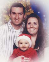 Christmas portrait of young man and woman, with baby in red Santa's cap.