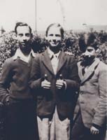 Three young boys in suit jackets, middle boy showing thumbs up.