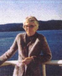 Coloured photo of older woman, with blue water in background.