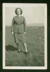 Young Joan in military uniform, standing in the distance outside. 