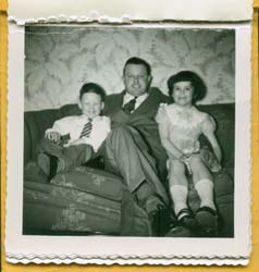 Father seated on couch in the middle of young boy and girl.