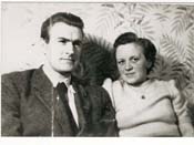Younger John and Kiersten, sitting in front of flower-patterned wallpaper.