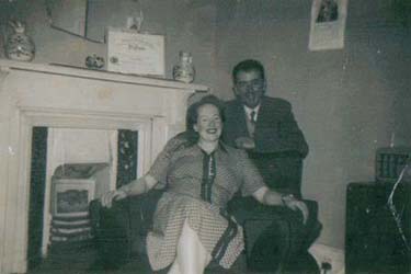 Man and woman seated in front of the fireplace.