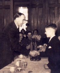 Young boy shaking the hand of an older gentleman with other people clapping. 