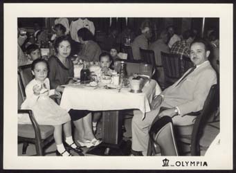 Mother, father and children seated at dinner table on the ship.
