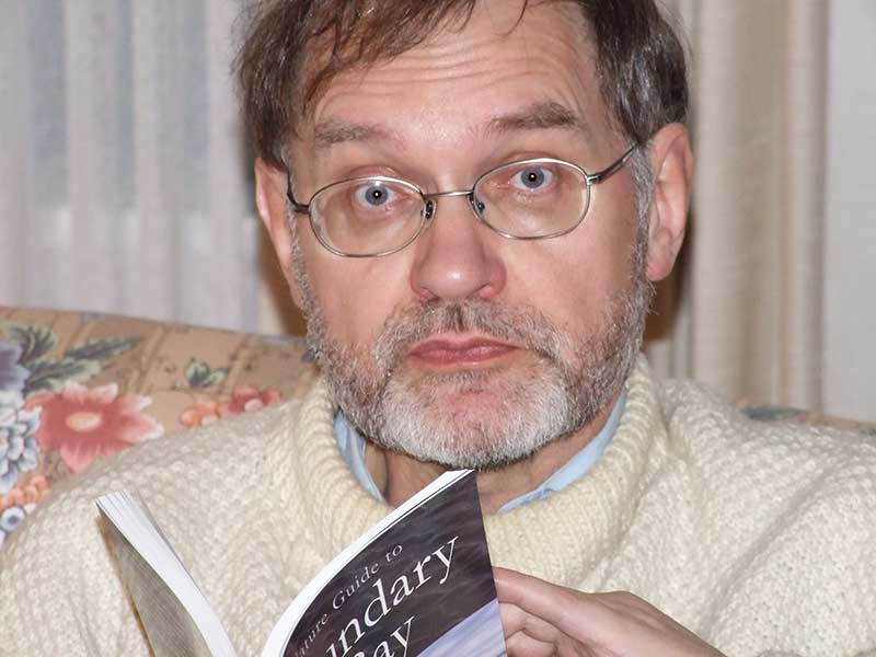 Man wearing glasses, reading a book.