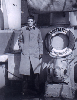 Young Jack in overcoat, standing next to a lifebuoy pointing to Aquitania.