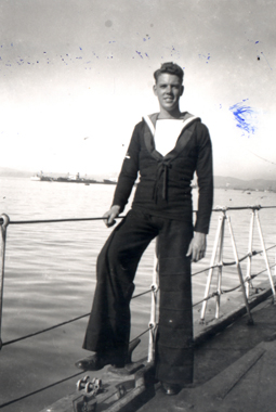 Young Jack in a sailor’s outfit, standing against the railing of a boat.