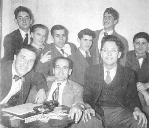 Young men sit around a table and appear very happy.