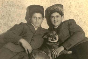 Two young boys wearing fur hats, a dog between them.