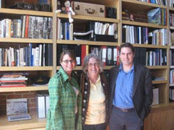 Woman standing between young woman and man, in front of library shelf.