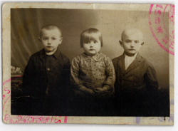 Old stamped passport ID photograph with three small children.