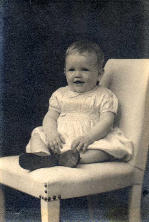 Small baby girl sitting on a chair.